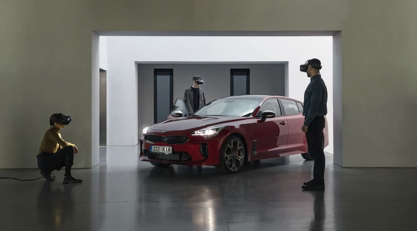 trois personnes portant des casques VR entourant un véhicule rouge